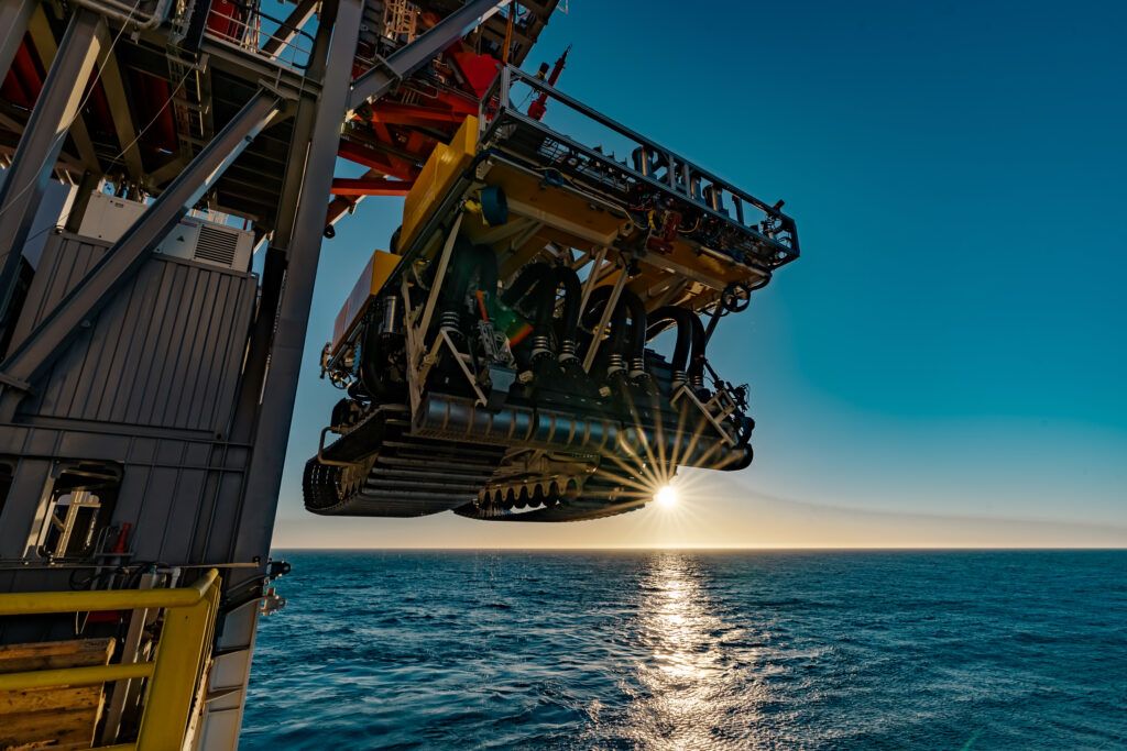 Photo of a deep sea mining machine being lowered into the ocean from a ship. Image credit: The Metals Company(@themetalsco) / Twitter