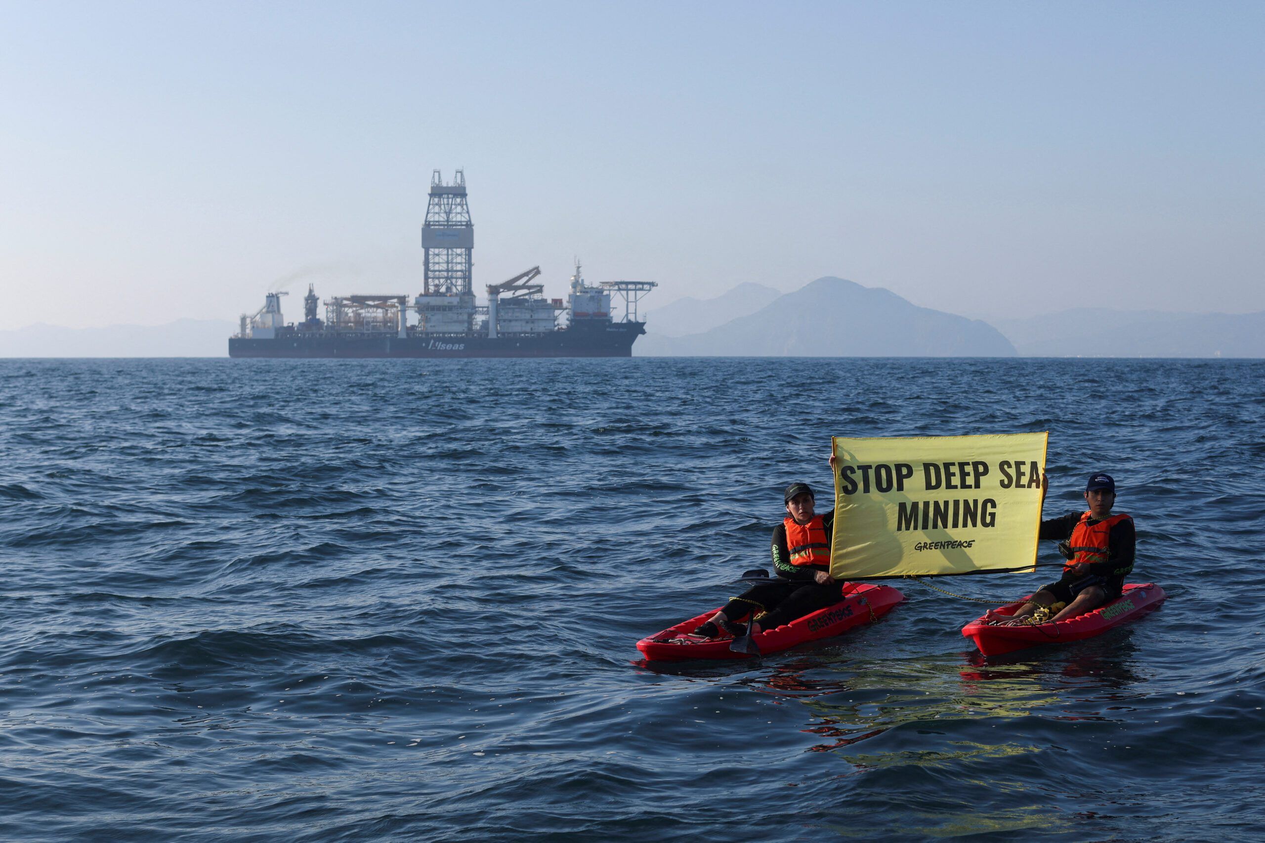 Two kayaks with Greenpeace activists inside hold a sign saying "Stop Deep Sea Mining" in front of a ship called 'The Hidden Gem' off the coast of Manzanillo, Mexico.